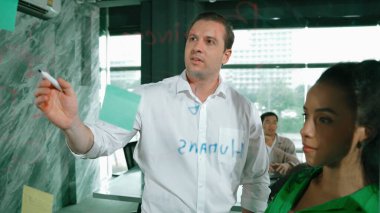 Yetenekli işadamı, cam duvara renkli yapışkan notlar yapıştırarak proje yöneticisine pazarlama fikrini sundu. Proje yöneticisi yatırımcıya projeyi gösteriyor, anlatıyor, gösteriyor. Yönlendirici.