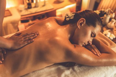 Beyaz kadın müşteri stres önleyici spa masajının keyfini çıkarıyor ve lüks otel ya da otelde sıcak mum ışığında güzellik teniyle eğleniyor. Sessiz.