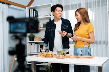 Aşçılar, sosyal medya yemek programı kanalı canlı yayın menü yemeği salatası, kepekli çörek ve video kameradan hamburger kaydı için telefonda yorum okuyorlar. İnfobahn.
