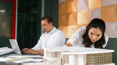 Mimar mühendis ekibinin portresi ve ofis tasarımı hakkında tartışmalar. Genç mühendis ev modelini ölçerken yönetici dizüstü bilgisayar kullanıyor. İş tasarımı konsepti. Yönlendirici.