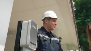 Teknisyen ev EV şarj istasyonu kurar, müşteri akıllı telefonunda şarj durumunu izlemek ve şarj takvimlerini evde ayarlamak için EV uygulamasına hizmet desteği sağlar. Titiz