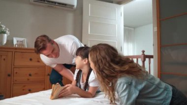 Mutlu modern aile hafta sonları küçük kızlarını neşeli bir şekilde uyandırır. Küçük kızlarına olan sevgilerini ve sevgilerini ifade ederler. Birlikte güler ve gülümserler. Titiz
