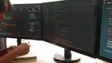 Yavaş çekim arkası yazılım geliştirici mühendisi bilgisayar programlama için birlikte çalışarak hata ayıklama kodunu çözüyor, ofiste monitörde karmaşık algoritmaları çözüyor. Filizlenen