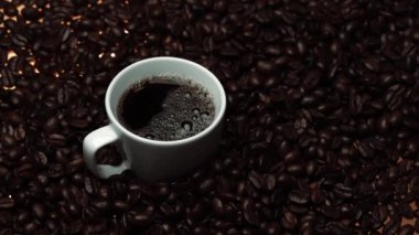 Kahve ya da kahve çekirdekli espresso manzarası. Taze kavrulmuş kahve çekirdeğini yakın çekimde ahşap masanın etrafına bir fincan americano ve aromatik akarsu ve tohum dumanı serpin. Geliştirilebilir.