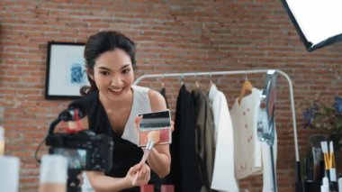 Kadın nüfuzlu kişi canlı yayın yapan video görüntülerini sosyal medya ya da blog üzerinden gözden geçiriyor. Kozmetik stüdyosu ışıklandırmalı mutlu genç kız çevrimiçi pazarlama oturumu yayını için..