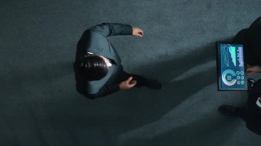 Profesyonel iş adamının yukarıdan görünüşü bir ekibe katıldı ve yönetici müdürle tokalaştı. Tabletteki hisse yatırım verilerini analiz etmek için birlikte çalışan ekip yavaş hareket ediyor. Müdürlük.