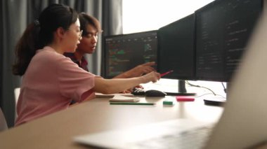 Yavaş çekim arkası yazılım geliştirici mühendisi bilgisayar programlama için birlikte çalışarak hata ayıklama kodunu çözüyor, ofiste monitörde karmaşık algoritmaları çözüyor. Filizlenen