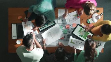 Planı elinde tutan inşaat mühendisi ekibinin en iyi görüntüsü ve dizüstü bilgisayar, proje planı ve planıyla masada duruyor. Yapışkan notları planlayan ve yazan yetenekli proje yöneticisinin havadan görünüşü. Sempozyum.