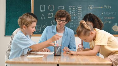 Zeki öğretmen, çeşitli çocuklar sınıf çalışması yapmak için birlikte çalışırken farklı çocukların zihin haritası çizdiği fikri açıklıyor. Çekici eğitmen öğretmek ve çalışmak hakkında konuşmak. Pedagoji.