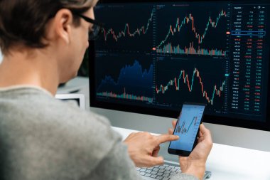 Akıllı borsa yatırımcıları ekranda akıllı telefon ile piyasa borsasını işaret ederek dizüstü bilgisayarın yanı sıra en yüksek dinamik yatırım oranını göstererek, modern işyerindeki veri planlamasına odaklanıyorlar. Bireysel.
