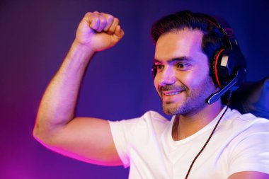 Kapanışta akıllı flamalar çevrimiçi oyun oynuyor kulaklık takıyor sosyal medyayla oynayan oyuncuya yumruk sallıyor. Esport beceri takımı oyuncusu dijital ortamda neon ışıklı stüdyo odasında. Tahmin et..
