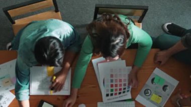 Ekip toplantısına katılıp fikir hakkında konuşurken proje yöneticisinin yazma fikrinin en üst görüntüsü. Renk paletine bakarken ve kağıda fikir yazarken profesyonel tasarımcı logosu. Sempozyum.