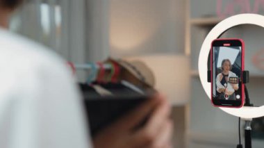 Arka plan etkileyicisi, vlog video gözden geçirme makyaj primi sosyal medya ya da blog kullanarak akıllı telefon yayınıyla canlı çekim yapıyor. İnternetteki pazarlama kaydı için kozmetik stüdyosu ışıklandırması olan kız.