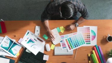 Kulaklıktan müzik dinlerken yetenekli iç dizayn grafiklerinin yukarıdan aşağı havadan görüntüsü. Proje yöneticisi kulaklıkla çalışırken ve rahat şarkılar dinlerken stüdyoda hareket ediyor. Sempozyum.