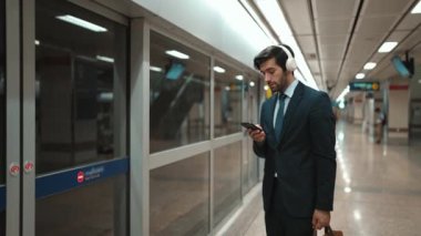 Proje yöneticisi tren istasyonunda şarkı seçmek için cep telefonu tutarken kulaklık takıyor. Zeki iş adamı bulanık geçmişi olan treni beklerken saati kontrol ediyor. Sevinçli..