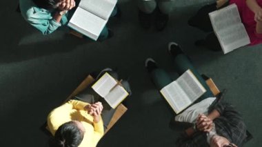 Yetenekli çeşitli duaların el ele tutuşması ve daireler çizerek Tanrı 'ya dua edişinin üst görüntüsü. Kucaklarda açık incille otururken el ele tutuşan insanların yukarıdan aşağı hava görüntüsü. Sempozyum.