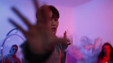 Çok kültürlü bir arkadaş kürsüde otururken Asyalı yetenekli bir dansçı modern müziğe geçiyor. Profesyonel dansçı, hipster takımı tezahürat yaparken ve desteklerken enerjik adımlar atıyor. Mutluluk.