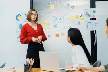 Profesyonel çekici kadın lider, modern iş toplantı odasında beyin fırtınası zihin haritalama istatistikleri ve renkli yapışkan notlar kullanarak yaratıcı pazarlama planını sunuyor. Tertemiz..