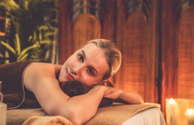 Beyaz kadın müşteri stres önleyici spa masajının keyfini çıkarıyor ve lüks otel ya da otelde sıcak mum ışığında güzellik teniyle eğleniyor. Sessiz.