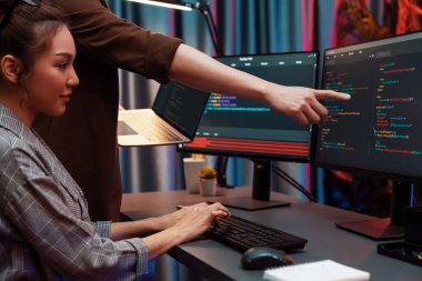 Modern ofisteki neon ışık odasında bilgi ağını gösteren dizüstü bilgisayarla iki ekranda veri çalıştıran akıllı web sitesi geliştirme kodlayıcı sistemini tartışan IT geliştiricilerinin ciddiyeti. İnfobahn.
