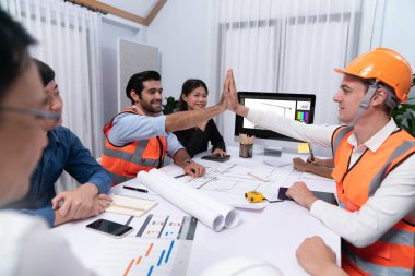 Çeşitli inşaat mühendisi ve müvekkil grupları, mimari proje üzerinde başarılı bir anlaşma yaptıktan, inşaat planını gözden geçirdikten ve toplantı masasında plan oluşturduktan sonra kutlama ve beşlik çakışma yaptılar.