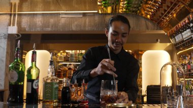 Zeki Asyalı barmen bardakta karıştırılmış alkol şurubunu buzla karıştırıyor. Çünkü kayanın üzerinde kamera var. Gece kulübünde taze kokteyl kokteylleri karıştırıyor. Vinosity.