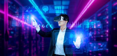 Finansal verileri analiz ederken veri merkezinde duran kulaklıklı bir iş adamı. Yönetici, pazarlama istatistiksel hologramını işaret ediyor ve karar verirken artırılmış gerçeklik gözlükleri kullanıyor. Yaratıcılık.