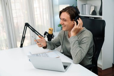 Sunucu kanalı, gülümseyen akıllı yayıncı kaydı, senaryosu ve akıllı telefonuyla sosyal medyada sohbet programı, kulaklık takarak modern ev stüdyosundaki video flamalarını kaydediyor. Bireysel.