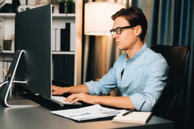 Akıllı iş adamı iş paragrafı dinamik pazarlama analizi planını analiz ediyor. Kağıt kağıtları ve bilgisayar monitörü raporlarını gece evdeki belge verileriyle karşılaştırmak için hazırlıyor. Bireysel.