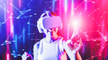 Zeki bir kadın, metaevreni birbirine bağlayan VR kulaklık takan neon ışıklarla çevrili duruyor. Gelecekteki siber uzay topluluğu teknolojisi. Sanal objeye parmağını kullanan zarif bir kadın. Halüsinasyon.