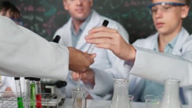 Çalışmaya hazırlanmak için kız eliyle biyokimyasal test tüpünü seçiyor. Zeki öğretmen ve bir grup mutlu çocuk BTMM fen sınıfında teoriyle kara tahtada deney yapıyorlar. Öğretim