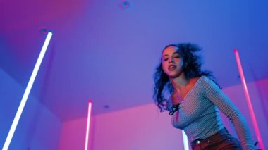 Latin dansçıların kameraya bakıp şehrin pop müziğiyle dans ettiği düşük açılı kamera. Profesyonel çekici hipster, mor veya neon ışıklı hip hop şarkısına geçiyor. Şık bir kumaş. Mutluluk.