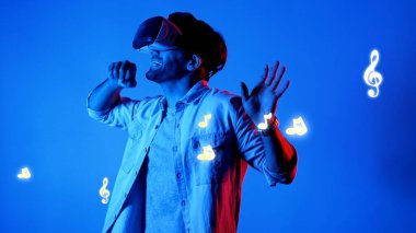 Mutlu dansçı VR gözlük takıyor ve havada süzülen notalarla şarkıya geçiyor. Dans ederken ve hareketli adımlar atarken sanal gerçeklik kulaklığı kullanan çekici bir adam. Aygıt.