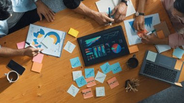 Yönetici, toplantı odasındaki meslektaşlarına mali grafiği açıklar. Farklı pazarlama ekibinin tabletle masada otururken fikir ve planlama stratejisini en üst düzeyde paylaşması. Cemaat.