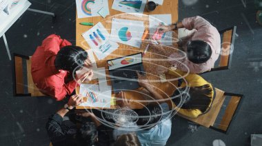 Küresel ağlarla finansal grafik üzerinde çalışan iş adamlarının en üst görüşü. Akıllı yönetici, iletişim sisteminin hologramıyla tablet istatistiklerine bakarken birlikte çalışıyor. Cemaat.
