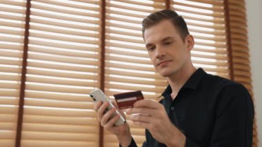 Masada oturan genç adam kredi kartıyla ödeme yapmak için akıllı telefondaki dijital cüzdanı ve uygulamayı kullanıyor. Mobil internet üzerinden alışveriş ve modern alımlar. Düzenle