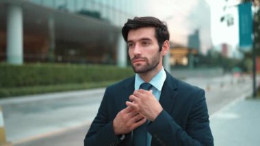 Profesyonel iş adamı yolda yürürken kravatı ayarlar. Yönetici şehre bakarken takım elbise giyiyor. Yatırımcı görüşmeye gitmeden önce kendini kontrol etmiş. Arka plan bulanık. Sevinçli..
