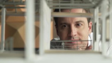 Kafkasyalı mimar mühendisinin yakın çekimi ev inşaatını denetlemek ve bina malzemelerini kontrol etmek. Proje yöneticisi modele dikkatlice bakarken kalemi işaret ediyor. Yönlendirici.