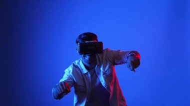 Akıllı oyuncu motosiklet sürerken yarış oyunu oynuyor. Günlük kıyafetleri olan, sanal gerçeklik gözlüğü takan ve meta veriye veya sanal dünyaya giren bir erkek model. Teknoloji. Aygıt.