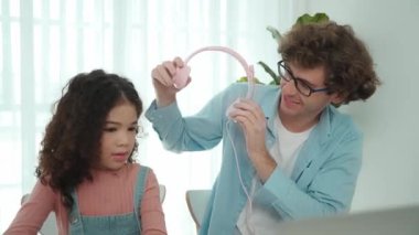 Beyaz bir baba kızına kulaklık takarken kız da kod öğreniyordu. Babam, mühendislik öğretirken liseli kızla ilgilenir ve dizüstü bilgisayar kullanarak Ai üretir. Çevrimiçi öğrenme. Pedagoji.