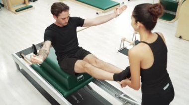 Beden eğitiminde birlikte pilates egzersizi yapan birkaç mutlu antrenör. Çekirdek gücü ve dengeyi arttırmak için reformcuda yüz poz veren İspanyol bir adam. Alışkanlık.