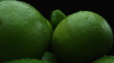 Limon dilimleri titizlikle bir yığın halinde, siyah arkaplana göre dizilmiş. Her bir kireç dilimi çarpıcı detaylar, canlı yeşil rengi ve baştan çıkarıcı dokusu ile yakalanır. Kapatın. Geliştirilebilir.
