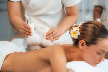 Sıcak bitkisel top spa masaj vücut tedavisi, masör kadın vücuduna nazikçe şifalı bitki torbası bastırıyor. Aromaterapi dinlenme sükuneti ve sükuneti kaplıca salonundaki atmosferi aydınlatıyor. Sessiz.