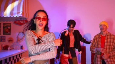 Hip hop müziğine yönelirken kameraya bakan beyaz dansçı. Profesyonel çeşitlilikteki dans ekibi stüdyoda pembe ışıkla enerjik hareketler ve çılgın adımlar sergiliyor. Mutluluk.