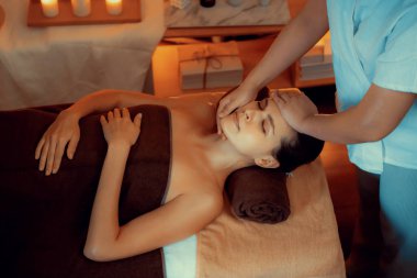 Beyaz kadın stres önleyici kafa masajı yapmaktan ve lüks otel veya otelde sıcak mum ışığında yüz güzelliği eğlencesi yapmaktan zevk alıyor. Sessiz.