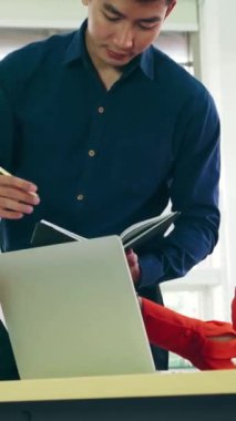 İki iş adamı toplantı odasında proje stratejisi hakkında konuşuyor. İş adamı, mali veri raporu hakkında sohbet ve tavsiyelerde bulunurken, modern işyerindeki iş arkadaşıyla proje planlamasını tartıştı.