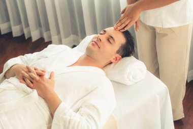 Beyaz adam stres önleyici kafa masajından ve lüks bir tatil beldesi veya otel spa salonundaki modern ışık ortamında yüz güzelliği eğlencelerini şımartmaktan hoşlanıyor. Sessiz.