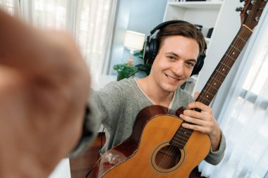 Akıllı şarkıcı görünümlü kamerada sunucu kanalı gitar tutarken, sosyal medya kanalında yayın yaparken, kulaklık takarken modern stüdyo kaydında video kaydedici olarak görülüyor. Bireysel.