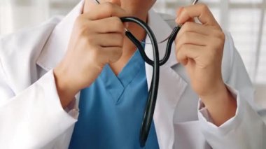 Hasta klinikte ya da hastane ofisinde doktor randevusuna gidiyor. Hastaların nabzını steteskopla kontrol edip risk faktörünü belirleyen doktor semptomları inceliyor. Ağır çekim. Katı.