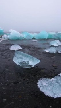 İzlanda 'daki Diamond Sahili' ndeki buzdağları. Elmas Plajı olarak bilinen kara kumsalda donmuş buz, Vatnajokull Ulusal Parkı 'ndaki Jokulsarlon Gölü' nden, Avrupa 'nın güneydoğusundaki İzlanda' dan akar..